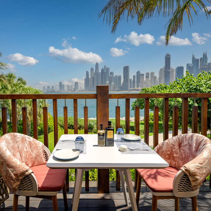 A table for two on an outside terrace, with stunning views of the water and Dubai's skyline behind